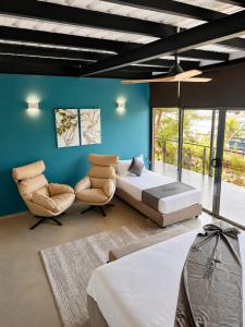 a bedroom with a bed and chairs and a blue wall at BlackRoots Unawatuna in Unawatuna