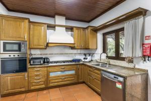 a kitchen with wooden cabinets and stainless steel appliances at Refúgio da Nelinha in Rio Caldo