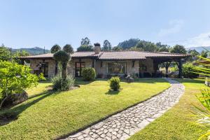 a house with a stone pathway in front of a yard at Refúgio da Nelinha in Rio Caldo