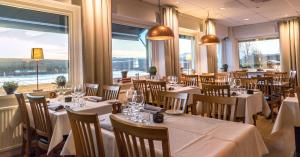 a restaurant with white tables and chairs and windows at Hotell Funäsdalen in Funäsdalen