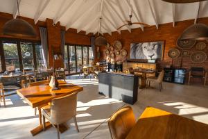 a restaurant with wooden tables and chairs and a television at Rockfig Lodge Madikwe in Madikwe Game Reserve