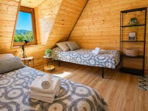 a bedroom with two beds in a log cabin at Portki - Cztery Pory Roku in Pszczeliny