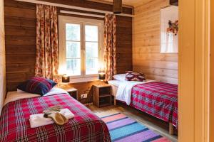 two beds in a room with wooden walls at ELK Aurora Lodge in Kakslauttanen