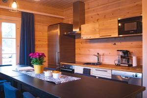 a kitchen with wooden walls and a counter with flowers on it at ELK Aurora Lodge in Kakslauttanen