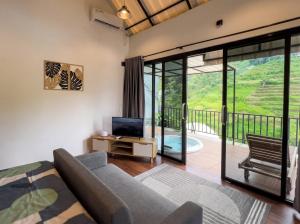 a living room with a couch and a tv and a balcony at Private Cabin in Bandung