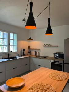a kitchen with a wooden table and two hanging lights at Le Verger in Aix-en-Provence