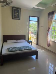 a bedroom with a bed in a room with a window at Quốc Ân Motel in Long Hai