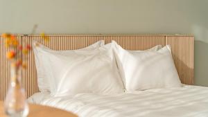 a bed with white pillows and a vase of flowers on a table at Namhae U9Stay in Namhae