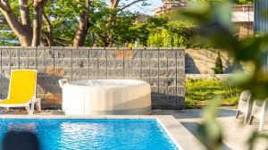 a pool with a hot tub and chairs next to a fence at Namhae U9Stay in Namhae