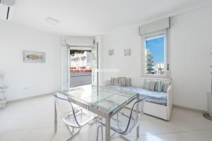 a dining room with a glass table and a bed at Residence Playa Grande Immobiliare Pacella in Lido di Jesolo