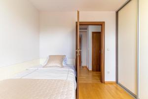 a white bedroom with a bed and a mirror at Sunny Day self check in in Rijeka