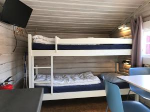 two bunk beds in a room with a table and chairs at Beverøya Hytteutleie og Camping in Bø