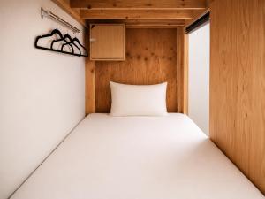 a bed in a small room with a wooden wall at Tokyo Guesthouse HIVE in Tokyo