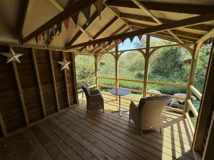 a large wooden porch with chairs and a table at Woody Nook Annexe in Pavenham
