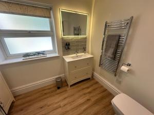 a bathroom with a sink and a window and a toilet at Woody Nook Annexe in Pavenham +30 photos