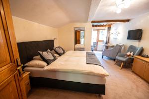 a bedroom with a large bed and a living room at Pension Hartenfels in Lech am Arlberg