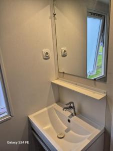 a bathroom with a sink and a mirror at Chalet te huur op het 'Eiland' Camping de Kleine Wielen Leeuwarden in Leeuwarden +2 photos
