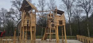 a wooden playground with a slide in a park at Chalet te huur op het 'Eiland' Camping de Kleine Wielen Leeuwarden in Leeuwarden