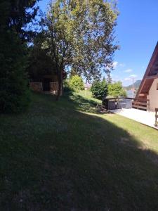 a grassy yard with a tree and a house at Vikendica Luka in Han Pijesak