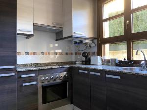 a kitchen with wooden cabinets and a sink and a stove at R2R - El Rincón de Luiña - 310A in Soto de Luiña