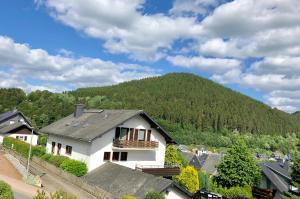 a white house with a mountain in the background at Willinger Perle 69 in Willingen