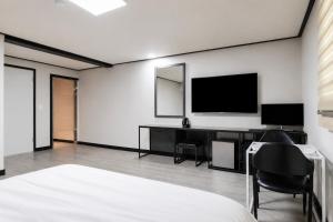 a bedroom with a desk and a television on a wall at Osan J Hotel in Osan