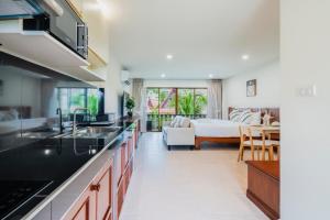 a kitchen with black counter tops and a living room at Westkey Patong Hotel in Patong Beach