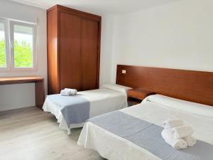 a hotel room with two beds and a window at Pensión San Antón in Sanxenxo +59 photos