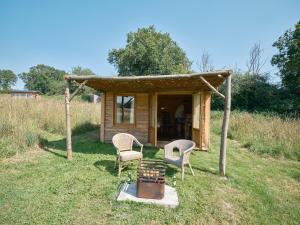 a small cabin with two chairs and a fire pit at Simple Basketmakers Hut Cabin for Two in Chiddingstone