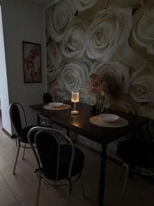a table with chairs and a wall with roses at Затишні апартаменти Східна Перлина in Vinnytsya