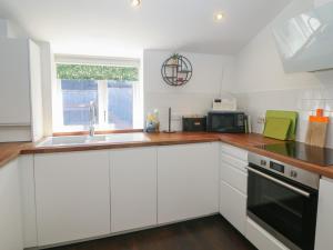 a kitchen with white cabinets and a sink at Cosy Cottage in Buxton +8 photos