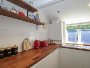 a kitchen with white cabinets and a wooden counter top at Cosy Cottage in Buxton