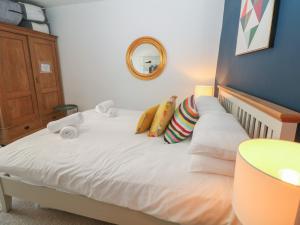 a bedroom with a white bed with pillows and a mirror at Cosy Cottage in Buxton
