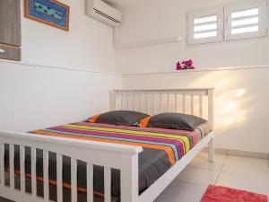 a bedroom with a white crib with a striped blanket at Appartement cosy Le Marin 60 m² + jardin in Le Marin