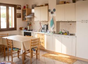 a kitchen with white cabinets and a table with chairs at Charming apartment in Nughedu Santa Vittoria - 90 m² with fireplace in Nughedu Santa Vittoria