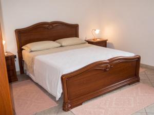 a bedroom with a wooden bed with white sheets and pillows at Charming apartment in Nughedu Santa Vittoria - 90 m² with fireplace in Nughedu Santa Vittoria +17 photos
