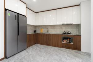 a kitchen with white cabinets and a stainless steel refrigerator at Caballos Apartment Capital Elite in Hanoi +11 photos
