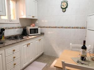 a kitchen with white cabinets and a microwave and a table at Charming house in Teror with garden in Teror