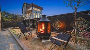 a outdoor fireplace with two chairs and a building at Chuncheon Poolhouse Epop in Chuncheon
