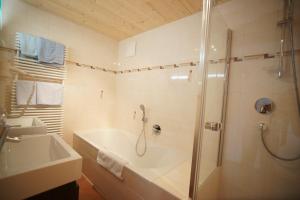 ein Badezimmer mit einer Dusche, einer Badewanne und einem Waschbecken in der Unterkunft Dorfappartements Söll in Söll