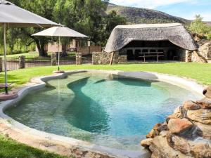 a swimming pool in a yard with an umbrella at Rietfontein Guest Farm in Ladismith