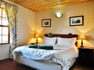 a bedroom with a large bed with two lamps and a window at Rietfontein Guest Farm in Ladismith