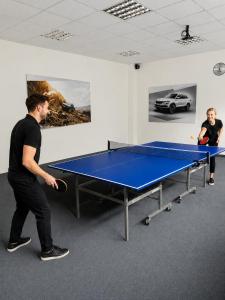 a man playing ping pong in a room with a ping pong table at Hotel Auto Jas in Nitra