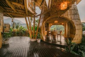 a large room with a wooden floor and a house with plants at Bamboo Villa with Amazing mount agung view in Selat