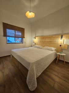 a bedroom with a large bed with a wooden headboard at Casa Saudade Beach House in Zambujeira do Mar