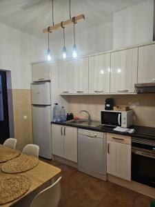 a kitchen with white cabinets and a table with chairs at Casa Saudade Beach House in Zambujeira do Mar