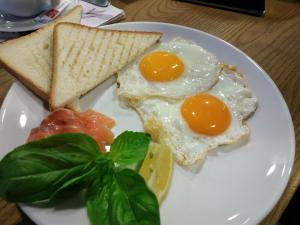 two fried eggs and toast on a plate with spinach at Harmónia Aqua Vendégház in Somogysárd