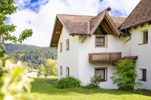 a white house with a wooden balcony on it at Apartments Schießstand in Avelengo