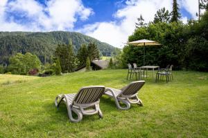 two chairs and a table with an umbrella in the grass at Apartments Schießstand in Avelengo
