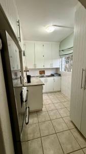 a kitchen with white cabinets and a tiled floor at Karlin #2, Frontline, Beach Access, Scottburgh in Freeland Park